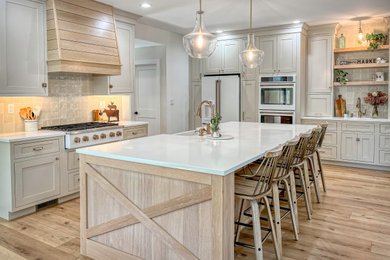 Open concept kitchen - large l-shaped light wood floor open concept kitchen idea in New York with a farmhouse sink, shaker cabinets, beige cabinets, quartz countertops, multicolored backsplash, ceramic backsplash, white appliances, an island and white countertops