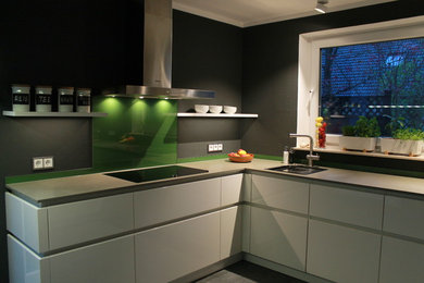 Offene, Mittelgroße Moderne Küche in U-Form mit flächenbündigen Schrankfronten, weißen Schränken, Küchenrückwand in Schwarz, Küchengeräten aus Edelstahl, Halbinsel, grauem Boden, Einbauwaschbecken, Arbeitsplatte aus Holz und Zementfliesen für Boden in Sonstige