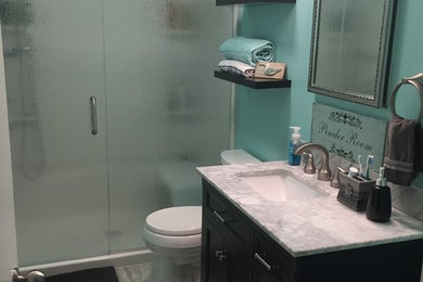 Alcove shower - mid-sized tropical kids' vinyl floor and beige floor alcove shower idea in Other with shaker cabinets, dark wood cabinets, a two-piece toilet, blue walls, an undermount sink, marble countertops, a hinged shower door and gray countertops