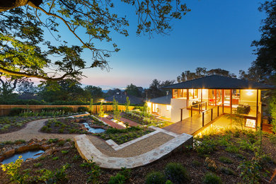 This is an example of an expansive contemporary sloped formal garden in Canberra - Queanbeyan with a garden path and gravel.