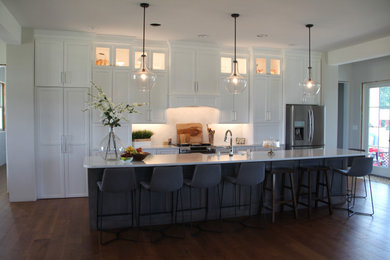 Inspiration for a mid-sized transitional u-shaped dark wood floor and brown floor enclosed kitchen remodel in St Louis with an undermount sink, shaker cabinets, white cabinets, quartz countertops, white backsplash, ceramic backsplash, stainless steel appliances, an island and white countertops