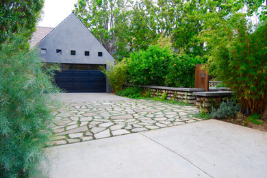 This is an example of a mid-sized modern drought-tolerant and partial sun front yard concrete paver and wood fence landscaping in Los Angeles.