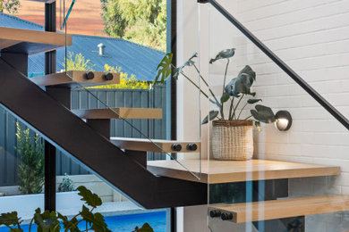 Photo of a mid-sized modern wood u-shaped staircase in Perth with open risers, glass railing and brick walls.