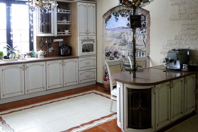 Photo of a mid-sized traditional l-shaped eat-in kitchen in Moscow with an undermount sink, raised-panel cabinets, light wood cabinets, solid surface benchtops, beige splashback, ceramic splashback, white appliances, ceramic floors, with island, multi-coloured floor and brown benchtop.