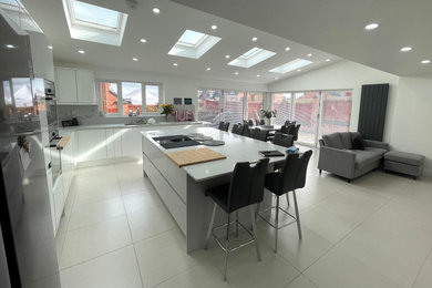 Modern grey and white open plan kitchen in Other with white cabinets, porcelain flooring, an island and white floors.