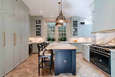 Large transitional u-shaped porcelain tile and brown floor kitchen photo in Charleston with an undermount sink, green cabinets, marble countertops, beige backsplash, an island, beige countertops and recessed-panel cabinets