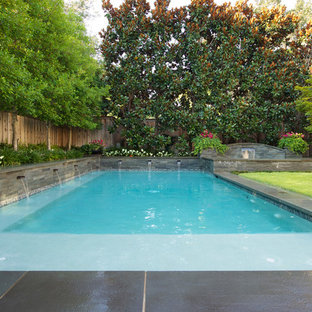 Inspiration for a large timeless backyard rectangular and stone infinity pool fountain remodel in Dallas