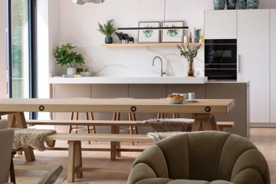 Photo of a medium sized contemporary single-wall open plan kitchen in Other with flat-panel cabinets, quartz worktops, black appliances, medium hardwood flooring and an island.