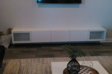 Ejemplo de sala de estar cerrada actual de tamaño medio con paredes grises, suelo de baldosas de porcelana, televisor colgado en la pared y suelo marrón
