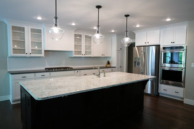 Inspiration for a large transitional l-shaped dark wood floor and brown floor eat-in kitchen remodel in Other with a farmhouse sink, shaker cabinets, white cabinets, marble countertops, white backsplash, subway tile backsplash, stainless steel appliances and an island