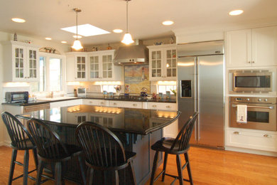 Mid-sized beach style l-shaped medium tone wood floor eat-in kitchen photo in San Luis Obispo with a double-bowl sink, shaker cabinets, white cabinets, granite countertops, multicolored backsplash, ceramic backsplash, stainless steel appliances and an island