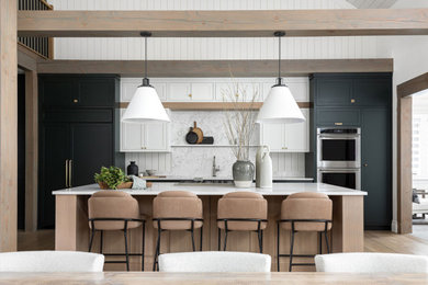 Large transitional single-wall eat-in kitchen in Toronto with flat-panel cabinets, light wood cabinets, white splashback, stainless steel appliances, with island and white benchtop.
