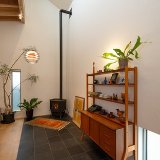 Idéer för funkis allrum med öppen planlösning, med vita väggar, skiffergolv, en öppen hörnspis, en spiselkrans i sten och svart golv