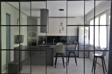Idee per una cucina chiusa con ante lisce, paraspruzzi nero, paraspruzzi con lastra di vetro, pavimento in gres porcellanato, pavimento grigio e top nero