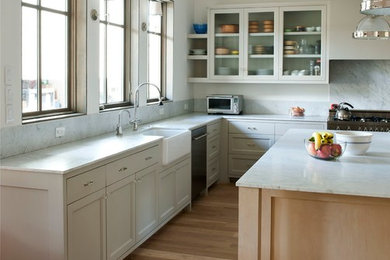Kitchen - large 1950s u-shaped medium tone wood floor kitchen idea in Houston with a farmhouse sink, shaker cabinets, white cabinets, marble countertops, white backsplash, stone slab backsplash, stainless steel appliances and an island