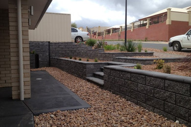 Photo of a mid-sized modern sloped garden in Adelaide with a retaining wall.