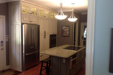 Inspiration for a small timeless galley medium tone wood floor kitchen remodel in Miami with an island, a double-bowl sink, recessed-panel cabinets, quartz countertops, brown backsplash, glass tile backsplash and stainless steel appliances
