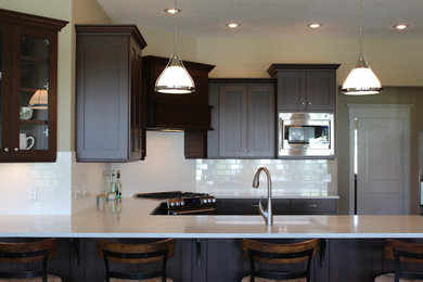 Eat-in kitchen - large traditional u-shaped eat-in kitchen idea in Other with an undermount sink, quartz countertops, white backsplash, subway tile backsplash, stainless steel appliances and a peninsula
