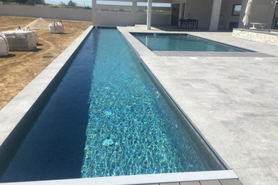 Imagen de casa de la piscina y piscina alargada clásica grande a medida en patio con adoquines de piedra natural