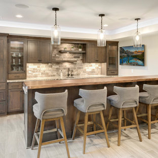 ミネアポリスのトランジショナルスタイルのおしゃれな着席型バー (アンダーカウンターシンク、フラットパネル扉のキャビネット、濃色木目調キャビネット、木材カウンター、マルチカラーのキッチンパネル、レンガのキッチンパネル、セラミックタイルの床、グレーの床、マルチカラーのキッチンカウンター) の写真