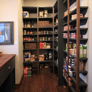 Mid-sized rustic kitchen pantry remodeling - Inspiration for a mid-sized rustic l-shaped medium tone wood floor and brown floor kitchen pantry remodel in Calgary with a farmhouse sink, raised-panel cabinets, dark wood cabinets, wood countertops, white backsplash, subway tile backsplash, stainless steel appliances, an island and brown countertops