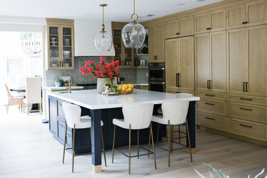 Example of a large medium tone wood floor and brown floor kitchen design in San Diego with a farmhouse sink, shaker cabinets, light wood cabinets, quartz countertops, blue backsplash, terra-cotta backsplash, paneled appliances, an island and white countertops