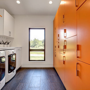 Foto de cuarto de lavado de galera, contemporáneo, de tamaño medio, con armarios con paneles lisos, encimera de cuarzo compacto, suelo de pizarra, lavadora y secadora juntas, puertas de armario naranjas y paredes blancas