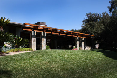 Photo of a large asian one-storey grey house exterior in Orange County with stone veneer, a gable roof and a shingle roof.