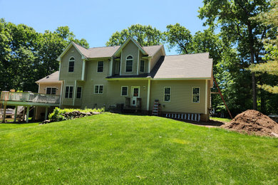 Inspiration for a large contemporary beige two-story vinyl and clapboard exterior home remodel in Bridgeport with a shingle roof and a brown roof