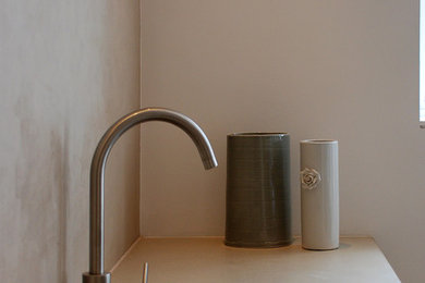 Modern kitchen in London with an integrated sink, flat-panel cabinets, beige cabinets, concrete worktops, beige splashback and stainless steel appliances.