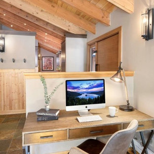 他の地域の小さいモダンスタイルのおしゃれなホームオフィス・仕事部屋 (ベージュの壁、淡色無垢フローリング、両方向型暖炉、石材の暖炉まわり、自立型机、茶色い床) の写真