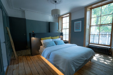 Modelo de dormitorio principal tradicional grande sin chimenea con suelo de madera clara, suelo marrón y paredes grises
