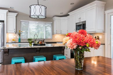 Open concept kitchen - mid-sized country l-shaped medium tone wood floor and brown floor open concept kitchen idea in Seattle with a double-bowl sink, raised-panel cabinets, white cabinets, quartz countertops, gray backsplash, porcelain backsplash, stainless steel appliances and an island