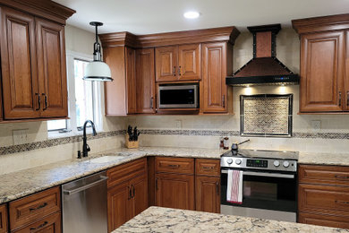 Kitchen - mid-sized traditional porcelain tile and beige floor kitchen idea in Other with an undermount sink, raised-panel cabinets, distressed cabinets, quartz countertops, beige backsplash, stone tile backsplash, stainless steel appliances, a peninsula and beige countertops