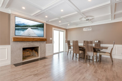 Large trendy light wood floor, beige floor, coffered ceiling and wainscoting dining room photo in New York with a standard fireplace, a stone fireplace and brown walls