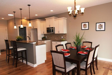 Inspiration for a mid-sized contemporary single-wall light wood floor open concept kitchen remodel in Chicago with white cabinets, granite countertops, beige backsplash, stainless steel appliances and an island