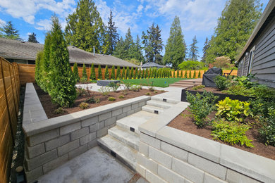 Photo of a huge modern backyard concrete paver and wood fence retaining wall landscape in Seattle.