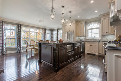 Inspiration for a huge timeless l-shaped dark wood floor and brown floor eat-in kitchen remodel in Other with an undermount sink, raised-panel cabinets, beige cabinets, granite countertops, gray backsplash, subway tile backsplash, stainless steel appliances and an island