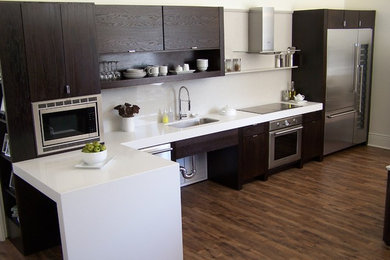 Kitchen - modern single-wall kitchen idea in Houston with a single-bowl sink, flat-panel cabinets, dark wood cabinets, quartz countertops, white backsplash, glass sheet backsplash and stainless steel appliances