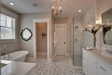Inspiration for a large transitional master bathroom in New York with white cabinets, a freestanding tub, a corner shower, gray tile, grey walls, mosaic tile floors, an undermount sink, recessed-panel cabinets, marble, quartzite benchtops, grey floor and a hinged shower door.