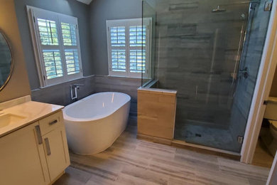 Large transitional travertine tile travertine floor and gray floor bathroom photo in Other with gray walls and a hinged shower door