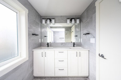 Example of a small kids' gray tile and porcelain tile vinyl floor, gray floor and single-sink bathroom design in Other with shaker cabinets, white cabinets, quartz countertops, a hinged shower door, white countertops, a niche and a built-in vanity