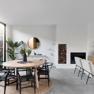Photo of a contemporary open plan dining in Melbourne with white walls, a ribbon fireplace, a brick fireplace surround and grey floor.