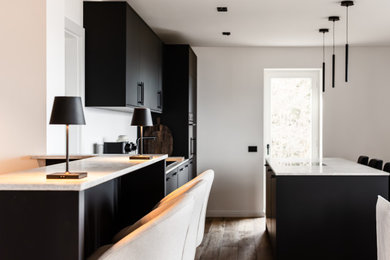 Immagine di una grande cucina minimalista con lavello da incasso, ante lisce, ante nere, top in marmo, parquet scuro e top beige
