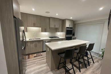 Inspiration for a modern kitchen remodel in Toronto with flat-panel cabinets, medium tone wood cabinets, beige backsplash, stainless steel appliances, an island and white countertops