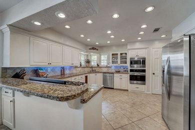 This is an example of a large kitchen in Houston with raised-panel cabinets, white cabinets, granite worktops, beige splashback, stainless steel appliances, no island, beige floors and beige worktops.