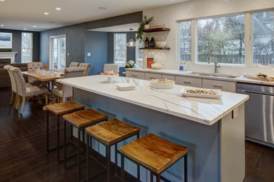 Inspiration for a mid-sized transitional u-shaped eat-in kitchen in New York with an undermount sink, shaker cabinets, white cabinets, quartz benchtops, white splashback, ceramic splashback, stainless steel appliances, dark hardwood floors, with island, brown floor and white benchtop.