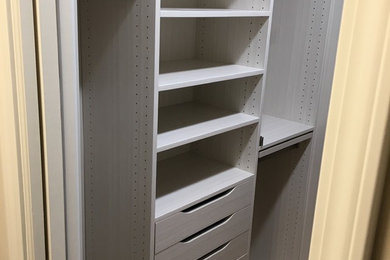 Diseño de armario vestidor unisex tradicional de tamaño medio con armarios con paneles lisos, puertas de armario blancas, suelo de madera en tonos medios y suelo marrón