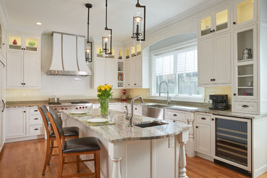 Inspiration for a mid-sized transitional u-shaped light wood floor and brown floor eat-in kitchen remodel in Boston with a farmhouse sink, white cabinets, white backsplash, an island, shaker cabinets, marble countertops, porcelain backsplash and stainless steel appliances