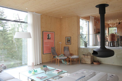 Exempel på ett mellanstort allrum med öppen planlösning, med beige väggar, betonggolv, en hängande öppen spis och grått golv